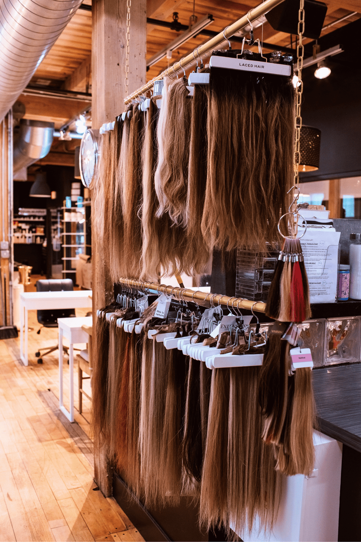Two-tiered standing rack with natural-colored hair extension packs in a salon | Quinn Vise Hair Design & Co. Hair Extensions in Holland, MI.